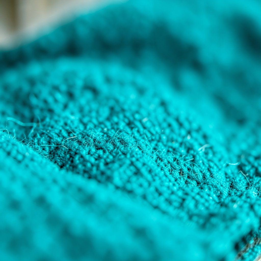 Abstract dark teal and charcoal woven texture, subtle diagonal pattern evoking a technical conference atmosphere
